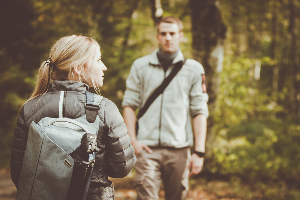 Mann und Frau spazieren mit Sporttaschen vom Hersteller ausgestattet durch einen Wald