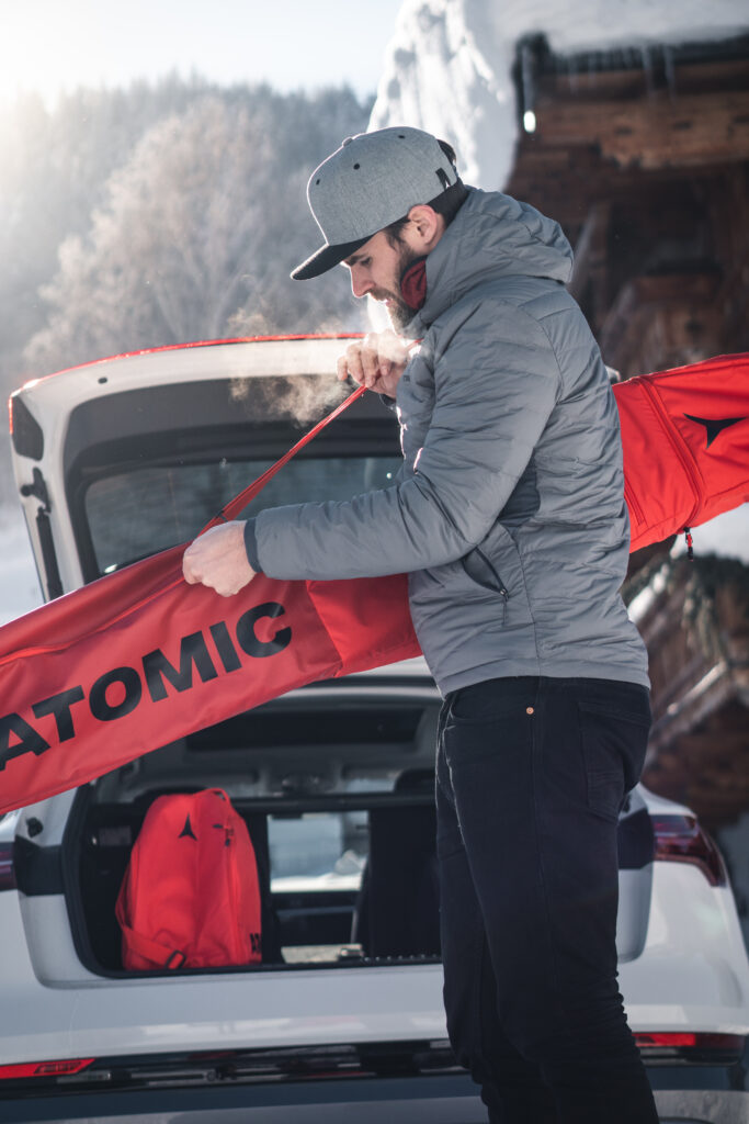 Mann trägt Skier in einer nach Maß gefertigten Sporttasche ins Auto